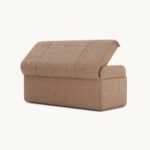De Adley Poef L is een moderne bruine ottoman met een gedeeltelijk geopend deksel dat verborgen opbergruimte onthult. De strakke lijnen en het minimalistische ontwerp bieden zowel functionaliteit als stijl.