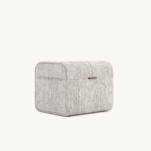 De Adley Poef S is een rechthoekige, stoffen opbergdoos met afgeronde randen, een subtiel gestreept design en een kleine handgreep aan de voorkant voor gemakkelijke toegang. Hij staat tegen een effen, lichte achtergrond.