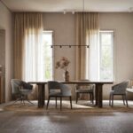 De moderne eetkamer straalt Jermain Stoel - Hout design uit, met een houten tafel met vier grijze gestoffeerde stoelen. Natuurlijk licht van hoge ramen met doorschijnende beige gordijnen en een vaas met gedroogde bloemen onder een laag hangende zwarte lamp versterken de elegantie.