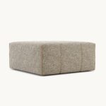 De Grant L Poef voetenbank, in een lichtgrijze tint met subtiele textuur en stikdetails aan de zijkanten, staat elegant tegen een gebroken witte achtergrond.