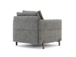 Zijaanzicht van de Matthew Armstoel, een fauteuil met bekleding van grijze stof, minimalistisch design en zwarte metalen poten, voorzien van een zacht rugkussen voor comfort en een eigentijdse uitstraling.