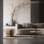 Een moderne woonkamer met een strakke Chloe 2-zitsbank, een ronde witte salontafel en een beige ottoman. Neutrale muren en een grote vaas met takken op de consoletafel versterken de serene ambiance.