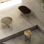 Moderne bijzettafels met metalen oppervlakken op een betonnen vloer, minimalistisch design in een lichte ruimte.