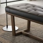 Moderne leren bank op houten frame, gestyled op een dik geweven vloerkleed in een stijlvolle woonkamer.