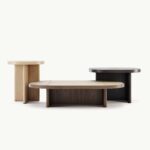 Drie moderne houten tafels in verschillende vormen en kleuren tegen een minimalistische achtergrond.