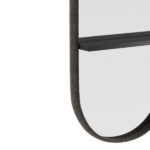 Een close-up van de Cleo L Spiegel toont een ovale spiegel met een donker, gestructureerd frame en een slank, zwart planchet, tegen een witte achtergrond om het minimalistische ontwerp te benadrukken.