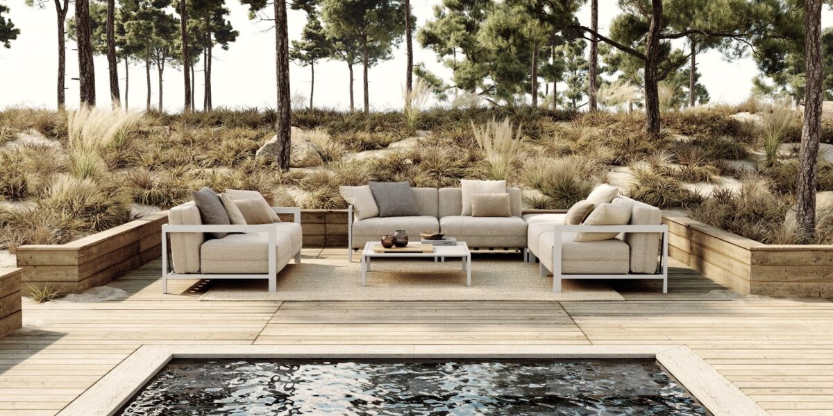 Luxe buitenmeubels op houten terras met zwembad en bosrijke achtergrond voor een ontspannen outdoor sfeer.