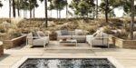 Luxe buitenmeubels op houten terras met zwembad en bosrijke achtergrond voor een ontspannen outdoor sfeer.