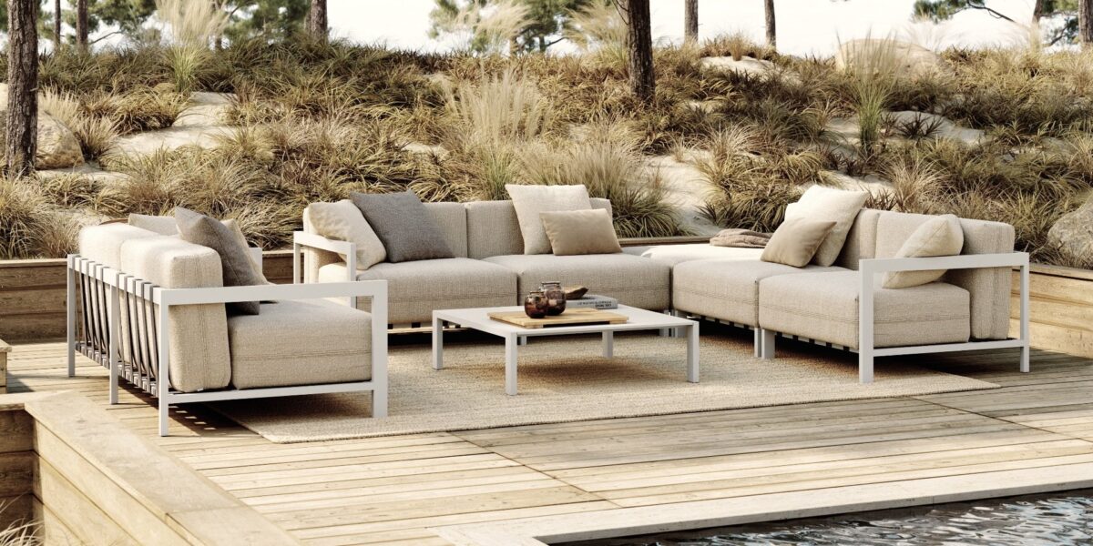 Luxe buitenmeubels op houten dek, omgeven door groene natuur, ideaal voor ontspanning en buitenleven.