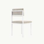 Minimalistische beige stoel met wit metalen frame, zijaanzicht, geschikt voor modern interieurontwerp.