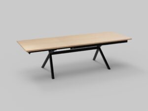 Een rechthoekige houten tafel met een lichte afwerking op een modern zwart metalen frame en schuine poten, geplaatst tegen een effen grijze achtergrond.