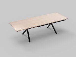 Een rechthoekige houten tafel met lichtgekleurd blad en zwarte, hoekige metalen poten staat op een effen grijze achtergrond. De tafel heeft een minimalistisch en modern design.