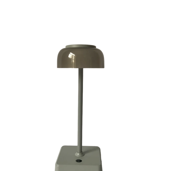 Een moderne tafellamp met een beige, koepelvormige kap en een strakke, verticale steel op een vierkante, grijze voet.