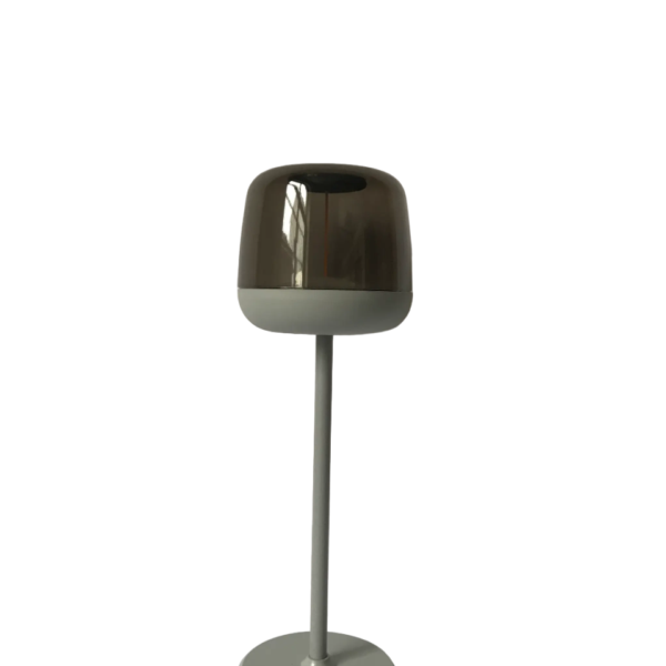 Een moderne tafellamp met een strak design, met een grijze basis en paal die een metalen, koepelvormige kap ondersteunt. De lamp is uitgeschakeld en geïsoleerd op een witte achtergrond.