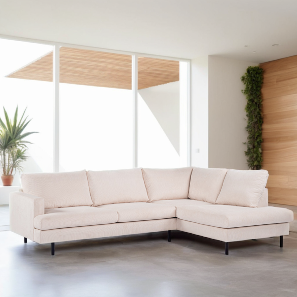 Een moderne woonkamer heeft een lichtbeige sectionele bank met strakke lijnen en zwarte metalen poten. De ruimte wordt verlicht door grote ramen en bevat minimale decoratie, zoals een potplant en een muur met groen.