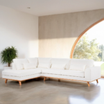 Een ruime woonkamer heeft een witte L-vormige sectionele bank met houten poten. De kamer heeft een gebogen, oversized raam dat natuurlijk licht binnenlaat en een potplant staat in de hoek. De vloer is van gepolijst beton.