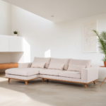 Een moderne, lichtbeige sectionele bank met houten poten in een lichte, minimalistische woonkamer. De kamer heeft een potplant, een kunstwerk aan de muur en strakke witte kasten, wat een schone en luchtige sfeer creëert.