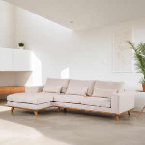 Een moderne, lichtbeige sectionele bank met houten poten in een lichte, minimalistische woonkamer. De kamer heeft een potplant, een kunstwerk aan de muur en strakke witte kasten, wat een schone en luchtige sfeer creëert.