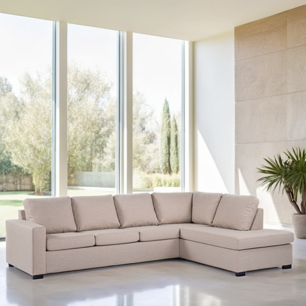 Een ruime, lichte kamer met grote ramen van vloer tot plafond, met een moderne, beige L-vormige bank. De elegante ruimte wordt aangevuld door een hoge potplant en biedt een sereen uitzicht op het groen buiten.