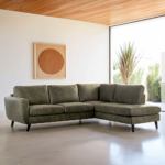 Moderne woonkamer met een 3 zits hoek rechts, stof Yuma 39, S156 groen bank, lichte vloer, groot raam, geometrische wandkunst, een hoge hoekplant en een plafond met houten lambrisering.