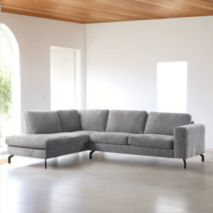 Een 3-zits hoekbank in Perfect Harmony 82-stof, R311 grijs, staat in een lichte, minimalistische woonkamer met witte muren, een plafond met houten lambrisering en grote ramen.