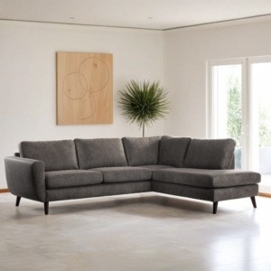 Moderne woonkamer met de 3 zits hoek rechts, stof Yuma 34, S520 taupekleurige hoekbank op een lichte vloer, met geometrische houten wanddecoratie, een decoratieve groene plant en grote ramen die natuurlijk licht binnenlaten.