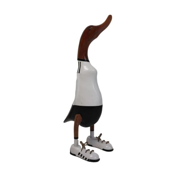 Houten eendensculptuur in een wit-zwarte outfit die lijkt op een sporttenue, met zwarte shorts en tennisschoenen. De snavel en kop zijn van natuurlijke houtkleur en de eend staat rechtop.