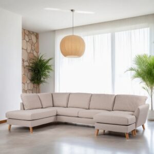 Een ruime, lichte woonkamer met een lichtbeige L-vormige bank op een gepolijste betonnen vloer. Een grote ronde hanglamp hangt aan het plafond. Twee groene potplanten voegen een vleugje natuur toe naast de met stenen geaccentueerde muur en de transparante gordijnen voor de ramen.