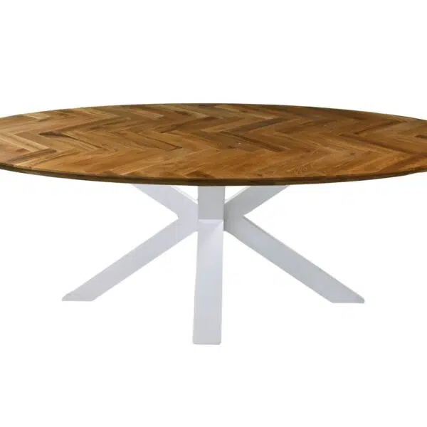 Een ronde houten tafel met een visgraatmotief op het bovenblad en een wit, modern kruispootonderstel. Het tafelblad heeft een warme, natuurlijke afwerking, die contrasteert met het strakke, moderne onderstel.