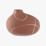 Een bruine, asymmetrische keramische vaas met een matte afwerking heeft witte, vloeiende lijnen die om het oppervlak heen wikkelen. De vaas heeft een kleine, ronde opening en een gladde, organische vorm.