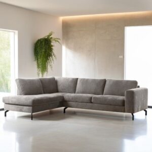 Moderne woonkamer met de 3-zits hoek links bank in de stof Perfect Harmony 04 R720 champagne, strakke zwarte poten, een groene potplant aan de muur en grote ramen die de ruimte vullen met natuurlijk licht.