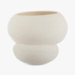 Een minimalistische, gebroken witte keramische vaas met een afgerond, dubbellaags ontwerp tegen een effen witte achtergrond. De vaas heeft een brede opening en een gestructureerd oppervlak.