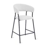 Een witte barkruk met een ronde rugleuning en zitting, met een zacht, pluche materiaal. Het heeft een zwart metalen frame en een voetenbankje, wat het een modern en minimalistisch design geeft.