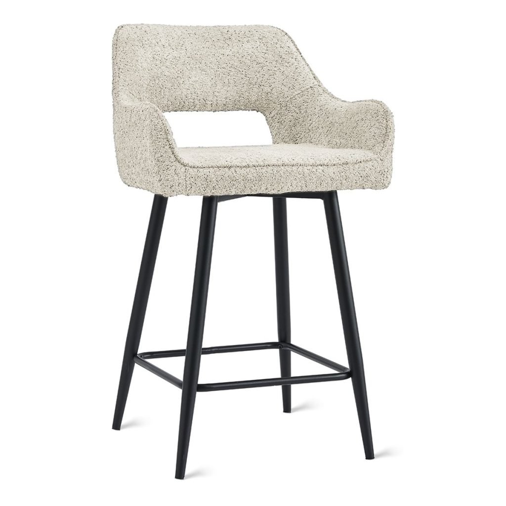 Een moderne barkruk met een beige stoffen zitting en rugleuning met textuur. Het heeft zwarte metalen poten met een vierkante voetensteun voor ondersteuning. Het algehele ontwerp is strak en eigentijds.