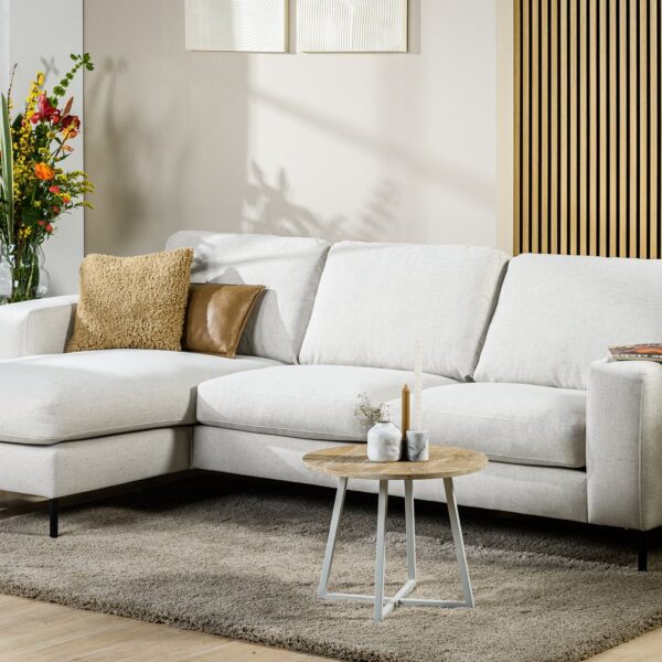 Moderne woonkamer met de 3-zitsbank CL L+R in de stof Valente V920 naturel, twee decoratieve kussens, een kleine ronde salontafel met kaarsen, een vaas met kleurrijke bloemen, een grijs vloerkleed en houten lambrisering.