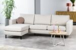 Moderne woonkamer met de driezitsbank CL L+R in Dillon D820 ivoor, een rond kussen, een houten salontafel met vazen en kaarsen, een dressoir, een roze lamp, een potplant en een licht vloerkleed op een tegelvloer.