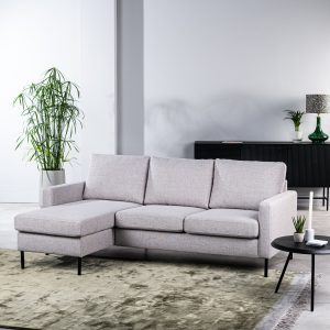 Moderne woonkamer met de 3-zitsbank CL L+R, stof Valente, V311 grijze hoekbank, groen vloerkleed, ronde zwarte bijzettafel met kleine plantjes, hoge potplant en zwart dressoir met decoratie tegen een witte muur.
