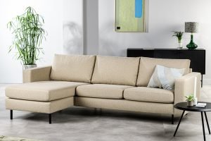 In een moderne woonkamer staat de 3-zitsbank CL L+R in D460 beige, een gestreept kussen, een klein, zwart rond bijzettafeltje met een plant, een hoge groene plant, een gedecoreerde consoletafel en abstracte wandkunst.