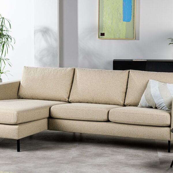 In een moderne woonkamer staat de 3-zitsbank CL L+R in D460 beige, een gestreept kussen, een klein, zwart rond bijzettafeltje met een plant, een hoge groene plant, een gedecoreerde consoletafel en abstracte wandkunst.