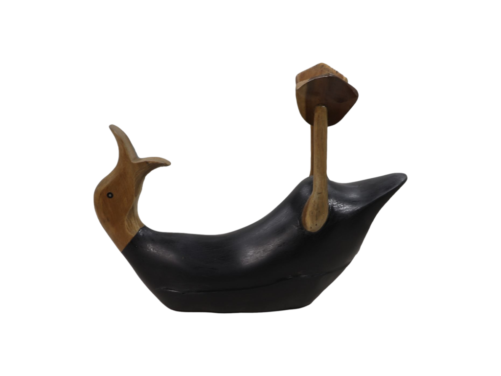 Een houten sculptuur van een gestileerde vogel in zwart en natuurlijk bruin. Het heeft een open snavel, vloeiende rondingen en een platte, verlengde staart met een dun, verticaal houten element aan de achterkant. De achtergrond is wit.