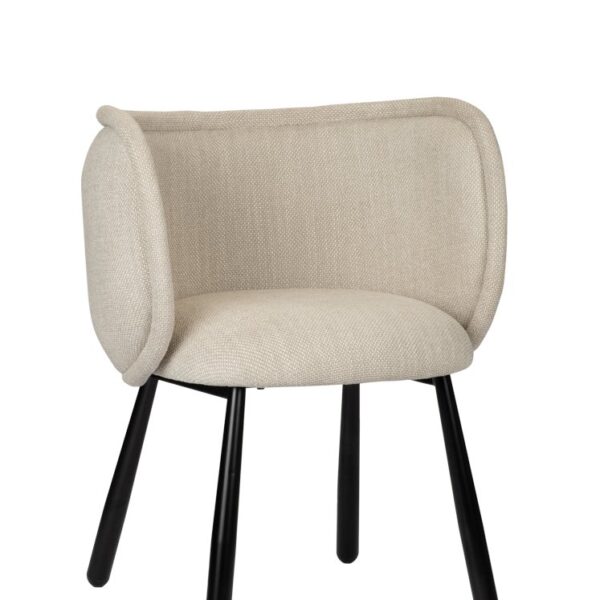 Een moderne beige stoffen stoel met afgeronde, gewatteerde rug en zitting, ondersteund door vier zwarte metalen poten. Het ontwerp oogt minimalistisch en eigentijds.