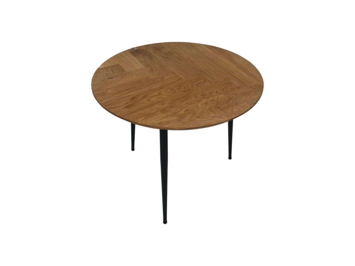 Een ronde houten tafel met een visgraatmotief op slanke zwarte metalen poten, tegen een witte achtergrond.