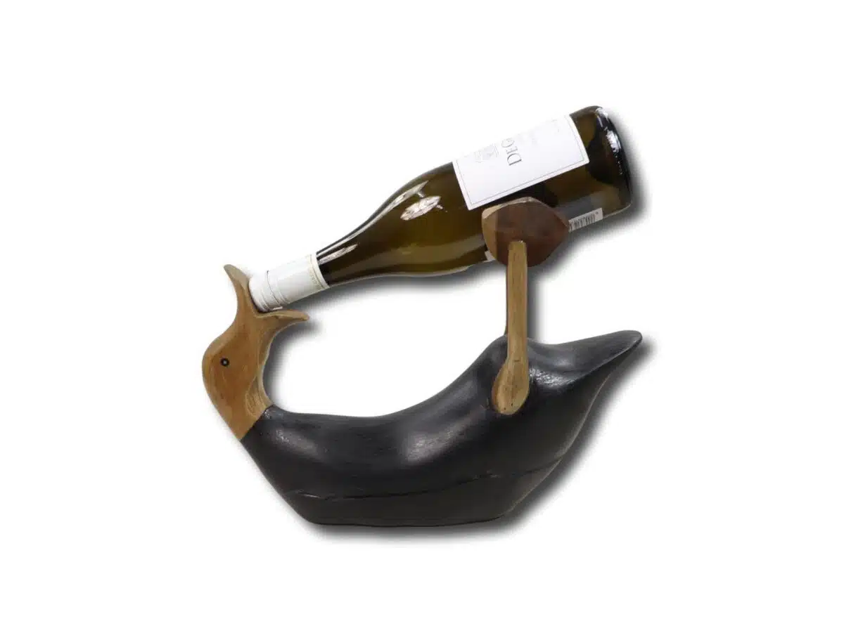 Een wijnhouder in de vorm van een walvis, gemaakt van donker hout, houdt een fles schuin vast. De fles rust op de staart van de walvis, waardoor een evenwichtige weergave ontstaat. De achtergrond is effen wit.