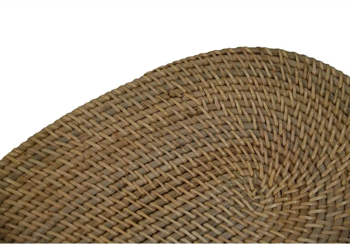Close-up van een geweven rietpatroon, met een cirkelvormige, strak gebreide textuur. De natuurlijke beige en bruine tinten van het materiaal creëren een rustieke, organische uitstraling. De achtergrond is effen wit, wat het geweven detail benadrukt.