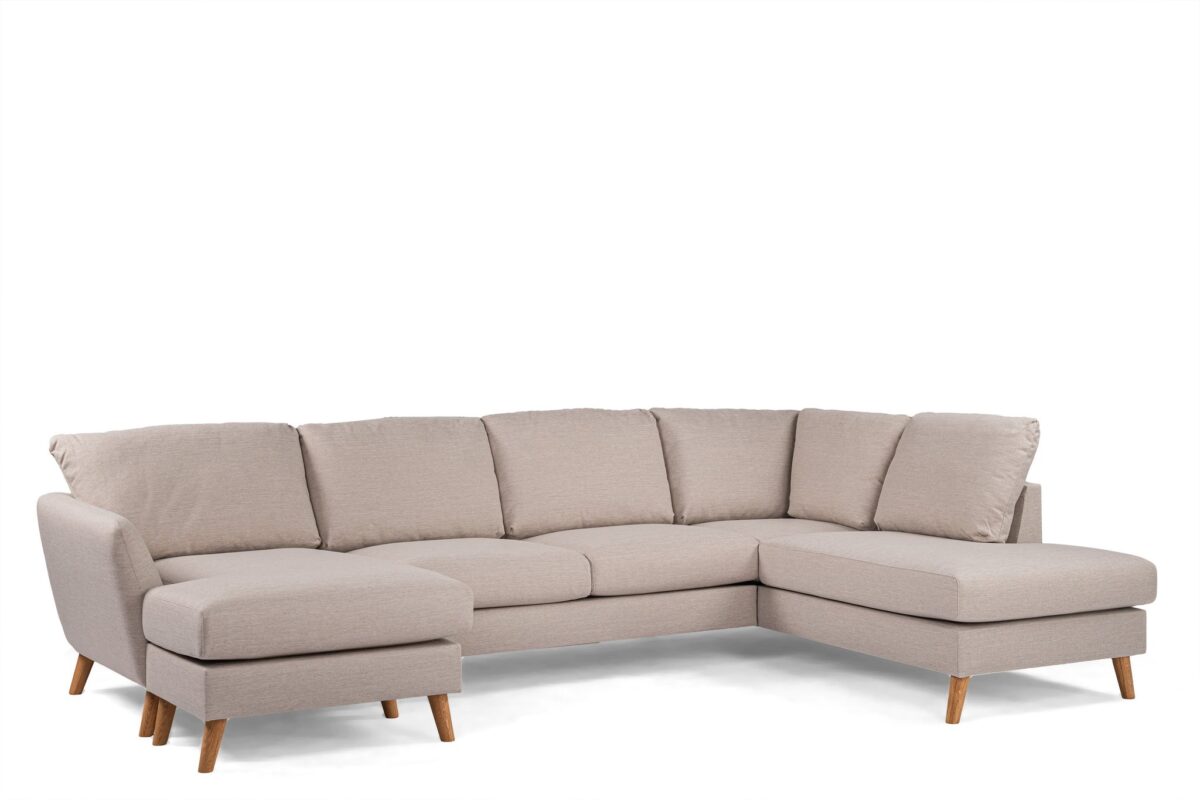 Een beige, L-vormige sectionele bank met lichte houten poten. De bekleding ziet er zacht en pluche uit, geschikt voor een ruime woonkamer. Het ontwerp is modern en minimalistisch, perfect voor comfortabel zitten.