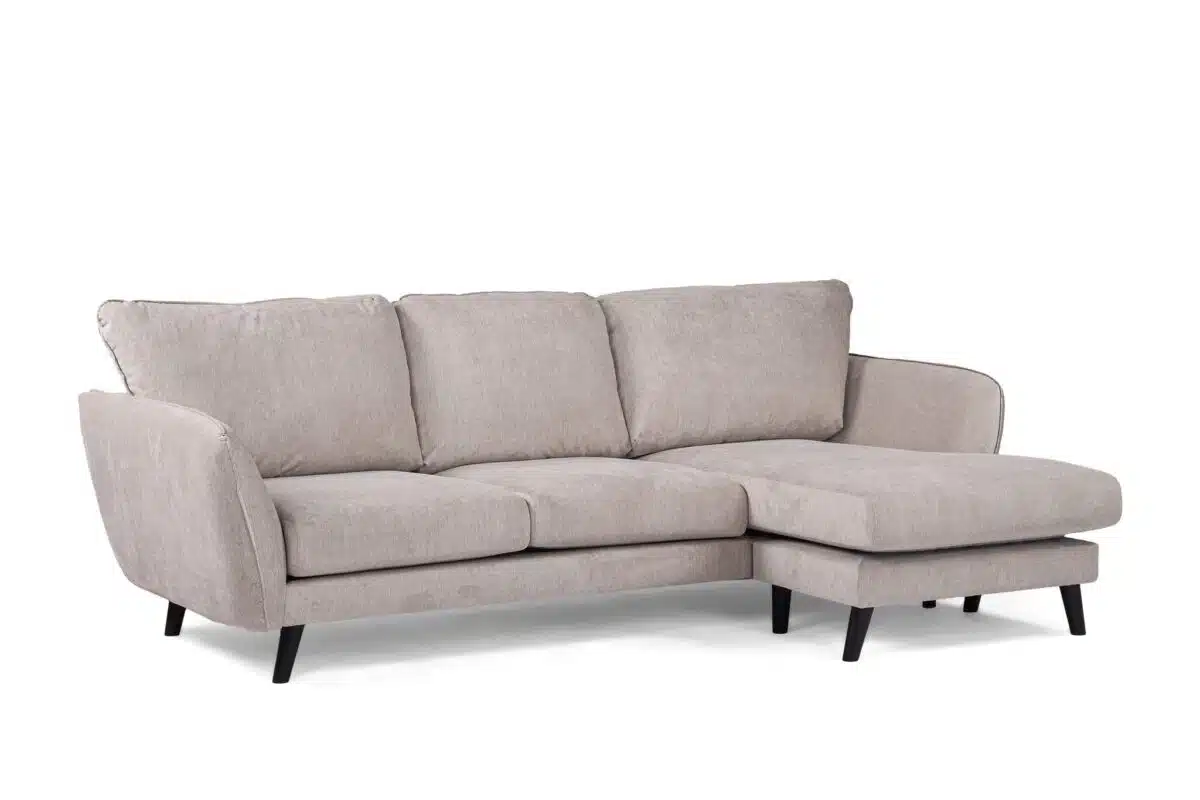 Een lichtgrijze, driezits sectionele bank met zachte kussens en een chaise longue aan de rechterkant. De bank heeft strakke zwarte poten en een modern design, dat comfort en stijl combineert.