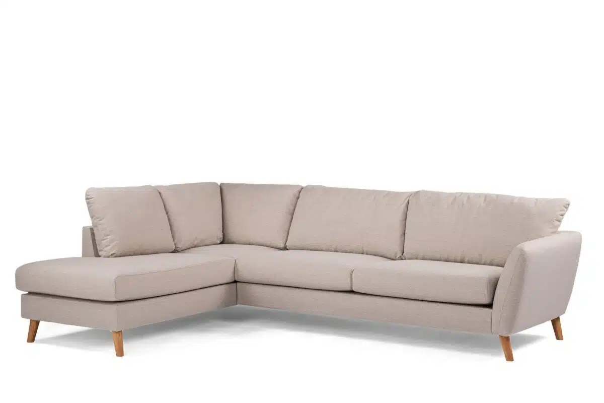 Een lichtbeige L-vormige sectionele bank met zachte kussens en houten poten, tegen een witte achtergrond. Het eigentijdse ontwerp heeft een chaise longue aan de linkerkant, wat comfortabele zitplaatsen biedt voor meerdere personen.