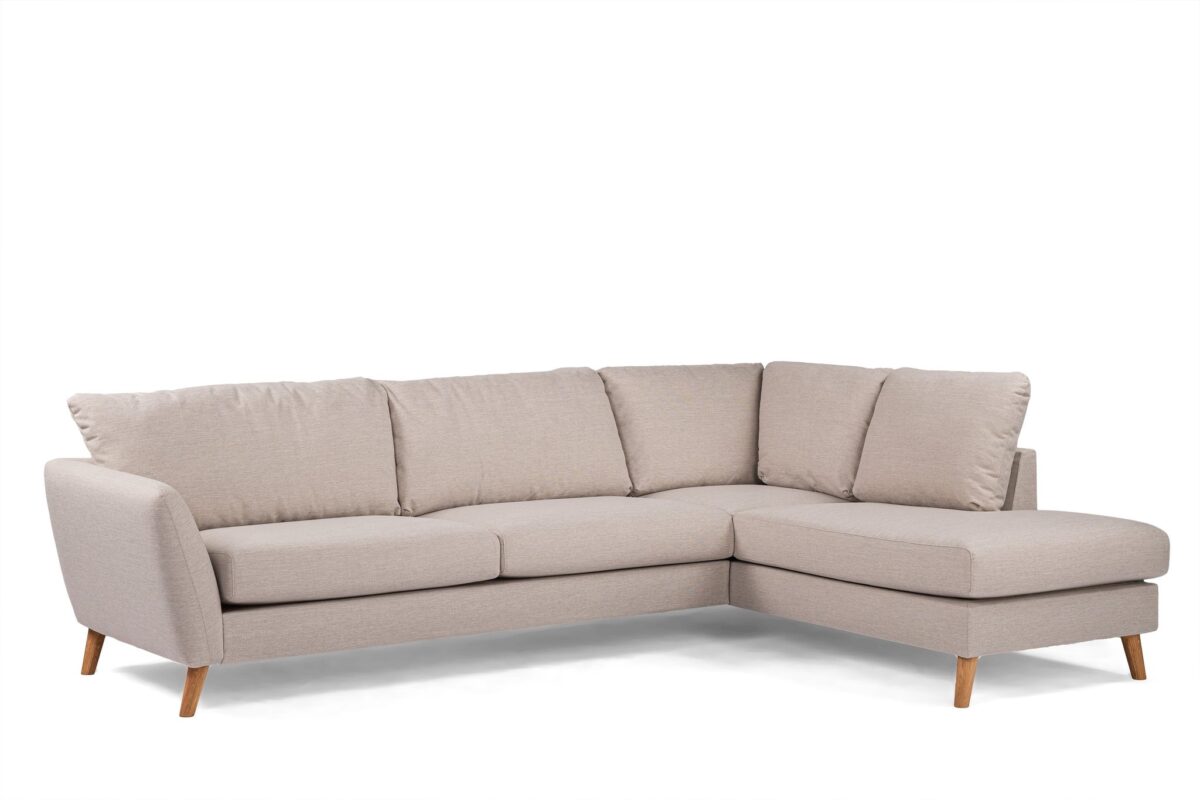 Beige L-vormige sectionele bank met schuine houten poten en zachte kussens. Het hoekontwerp biedt plaats aan meerdere personen, met een chaise longue aan de rechterkant, geschikt om te loungen in een moderne woonruimte.