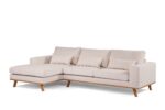 Een beige L-vormige sectionele bank met houten poten. Het heeft drie grote zitkussens, drie rugkussens en twee kleinere sierkussens. De bank heeft een minimalistisch, modern design met strakke lijnen.