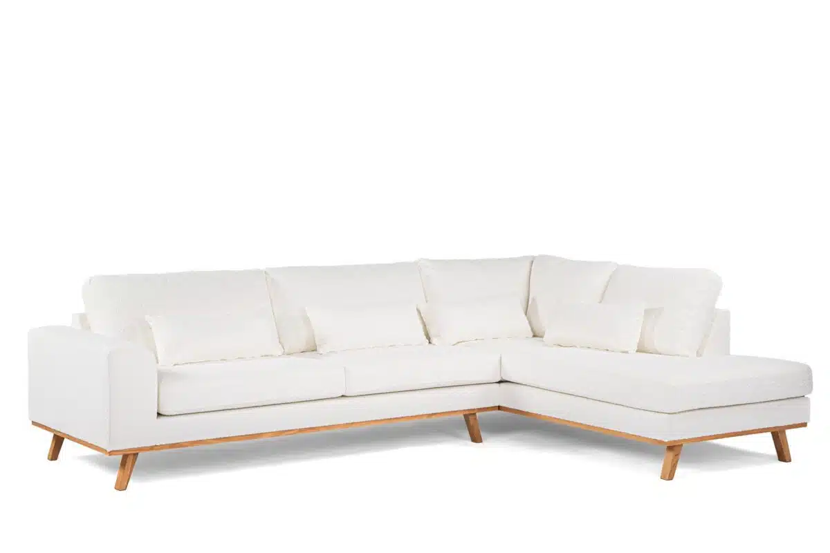 Een moderne witte sectionele bank met een chaise longue aan de rechterkant en houten poten. De bank heeft een strak design met meerdere zachte kussens, tegen een witte achtergrond.